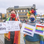 To kvinner holder oppe ulike plakater på russisk og norsk